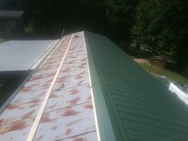 Old rusted panels beside newly installed green metal roofing — Wind Damage Roof Repair by Roofing Brothers in Woodbury